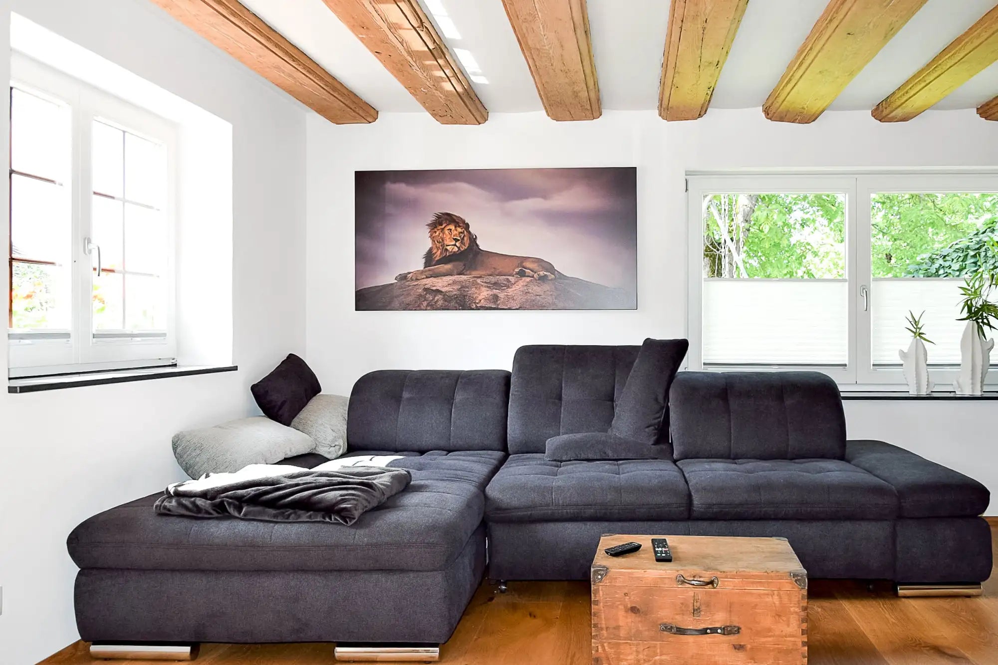 Divano angolare imbottito grigio scuro con cuscini decorativi neri e bianchi.